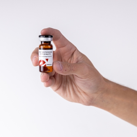 mans hand holding Male Excel testosterone cypionate vial