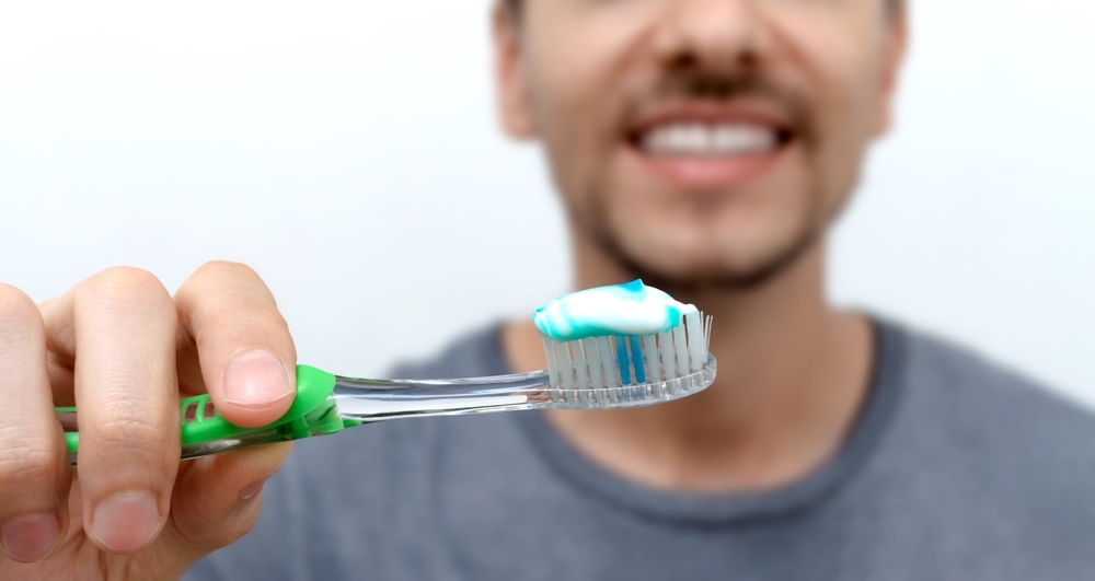 dental-health-heart-disease-smiling-man-brushing-his-teeth-with-toothbrush-and-toothpaste