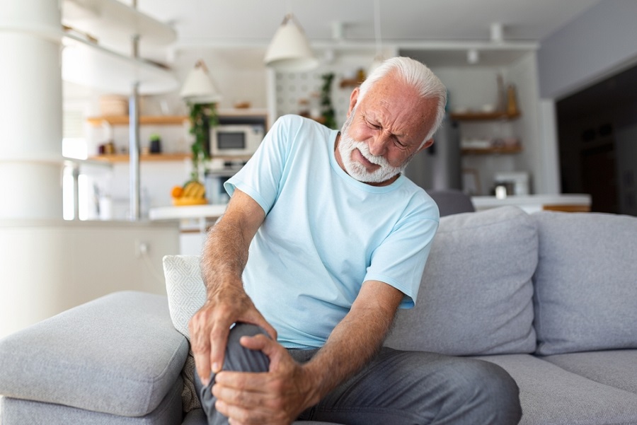 managing-chronic-pain-elderly-man-sitting-on-couch-holding-his-knee-in-pain managing-chronic-pain-elderly-man-sitting-on-couch-holding-his-knee-in-pain