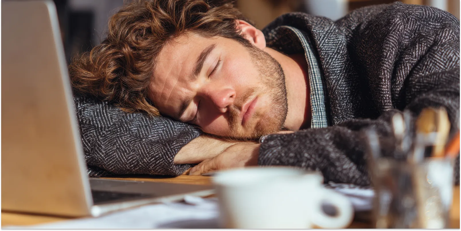 What Causes Low Energy in Men? Understanding the Real Reasons Behind Fatigue Image of an exhausted man asleep by his laptop. Hero image for article on What Causes Low Energy in Men